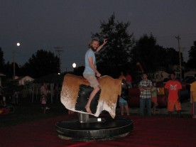 Shane Reichart riding a mechanical bull at dusk